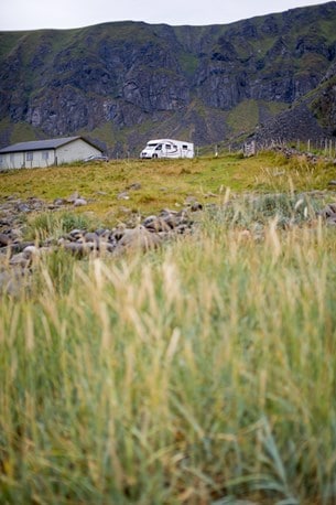 Parkerade med berg bakom och strandängar framför.